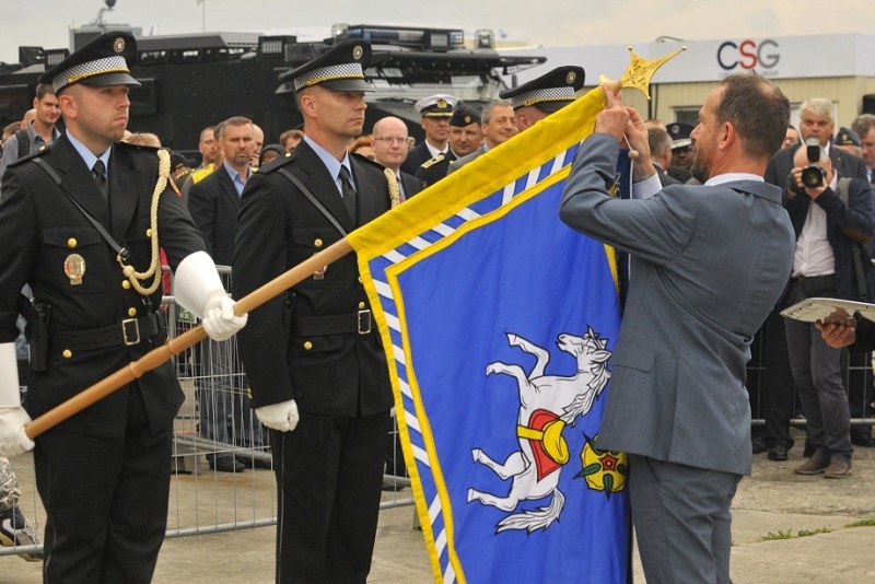 Primátor T. Macura dekoruje prapor městské policie čestnou stuhou.
