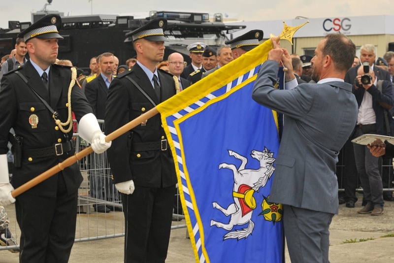 Primátor T. Macura dekoruje prapor městské policie čestnou stuhou.