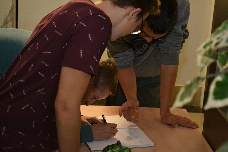 Hosté se zapisují do návštěvní knihy výstavy.